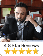 Aurelio Garza, Esq. attorney on the phone and wrote something on paper with 4.8-star reviews - Law Office Of Aurelio Garza PLLC