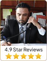 Aurelio Garza, Esq. attorney on the phone and wrote something on paper with 4.9-star reviews - Law Office Of Aurelio Garza PLLC